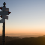 "Signpost at sunrise offering direction for selling a home in Ohio with scenic background"