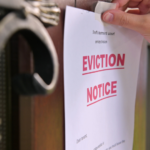 A close-up view of a person's hand affixing an 'Eviction Notice' to a door, indicating the start of the eviction process for a tenant in Ohio.