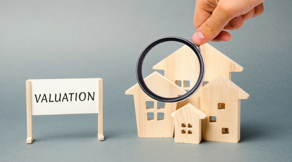 "Hand holding magnifying glass over wooden house models next to a 'VALUATION' sign, depicting the home appraisal process in Ohio."