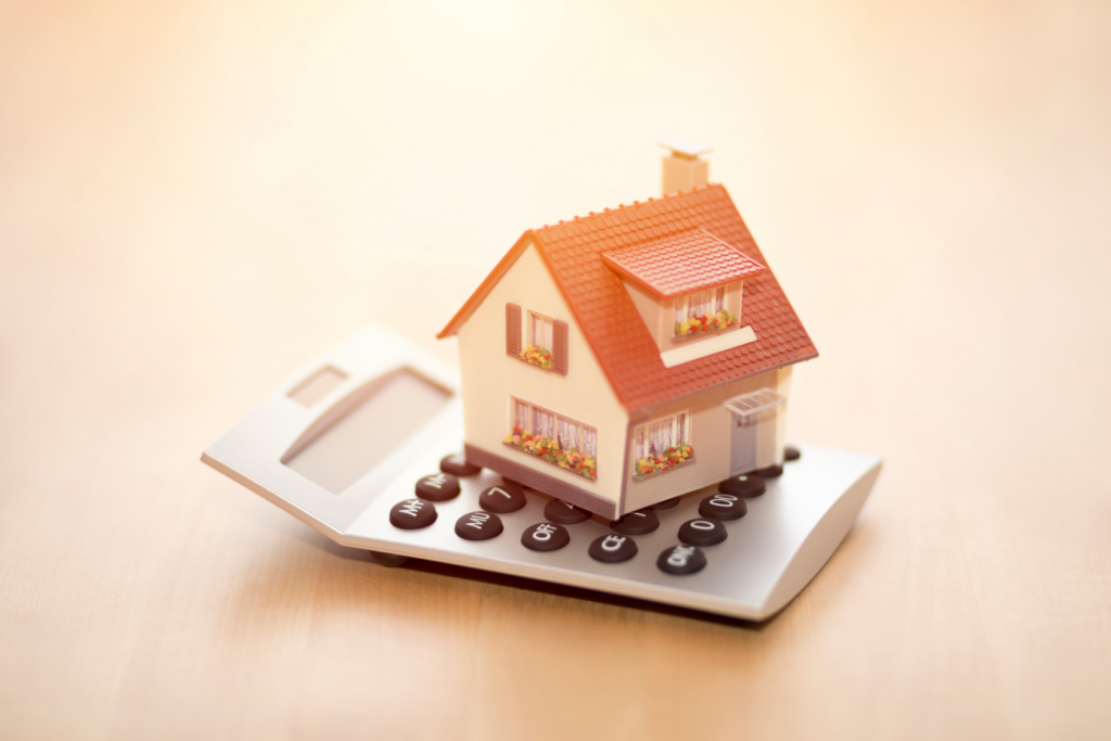 Miniature house on calculator representing calculating tax implications for rental property sales in Ohio.