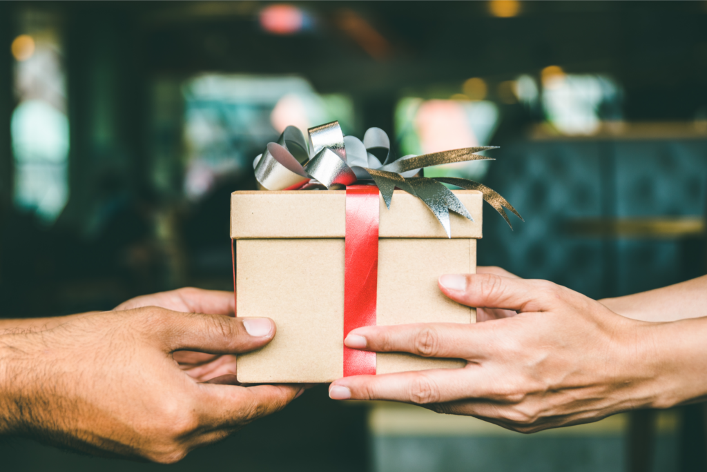 Handing over a gift-wrapped property deed in Ohio, symbolizing real estate gifting as part of estate planning.