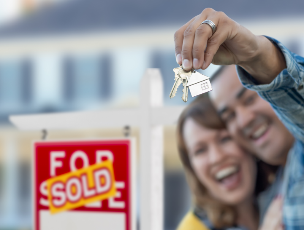Happy couple with new house keys in front of sold sign in Ohio