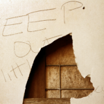 Keep Out sign on a broken wooden surface indicating a squatter's presence in an Ohio property.