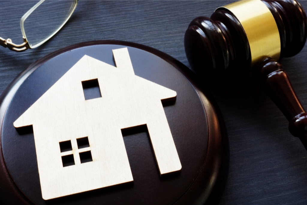 Wooden house model and judge's gavel symbolizing Ohio real estate law for property sales.