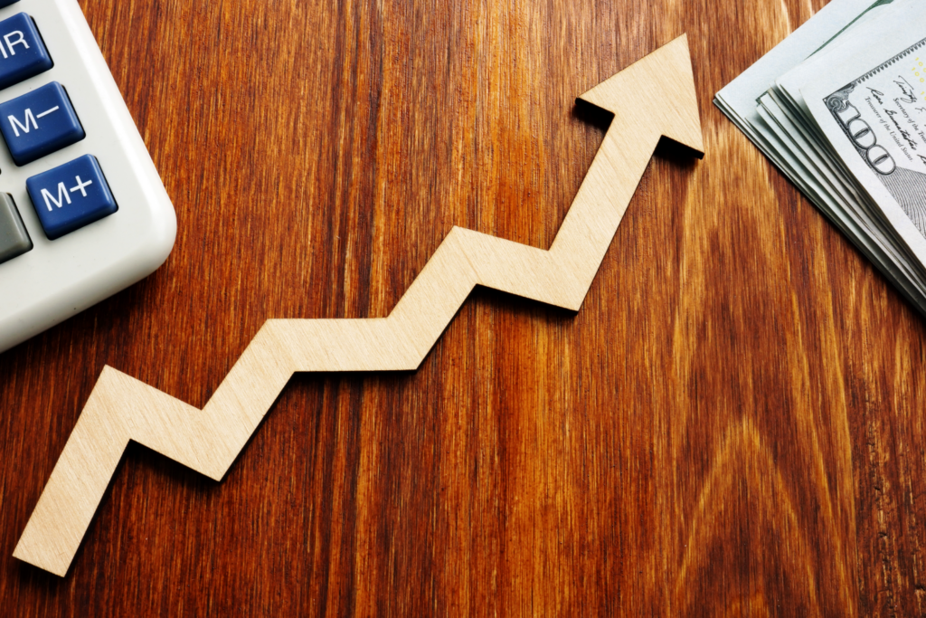 Wooden arrow pointing upwards alongside a calculator and cash, depicting rising profits in Ohio rental property sales.