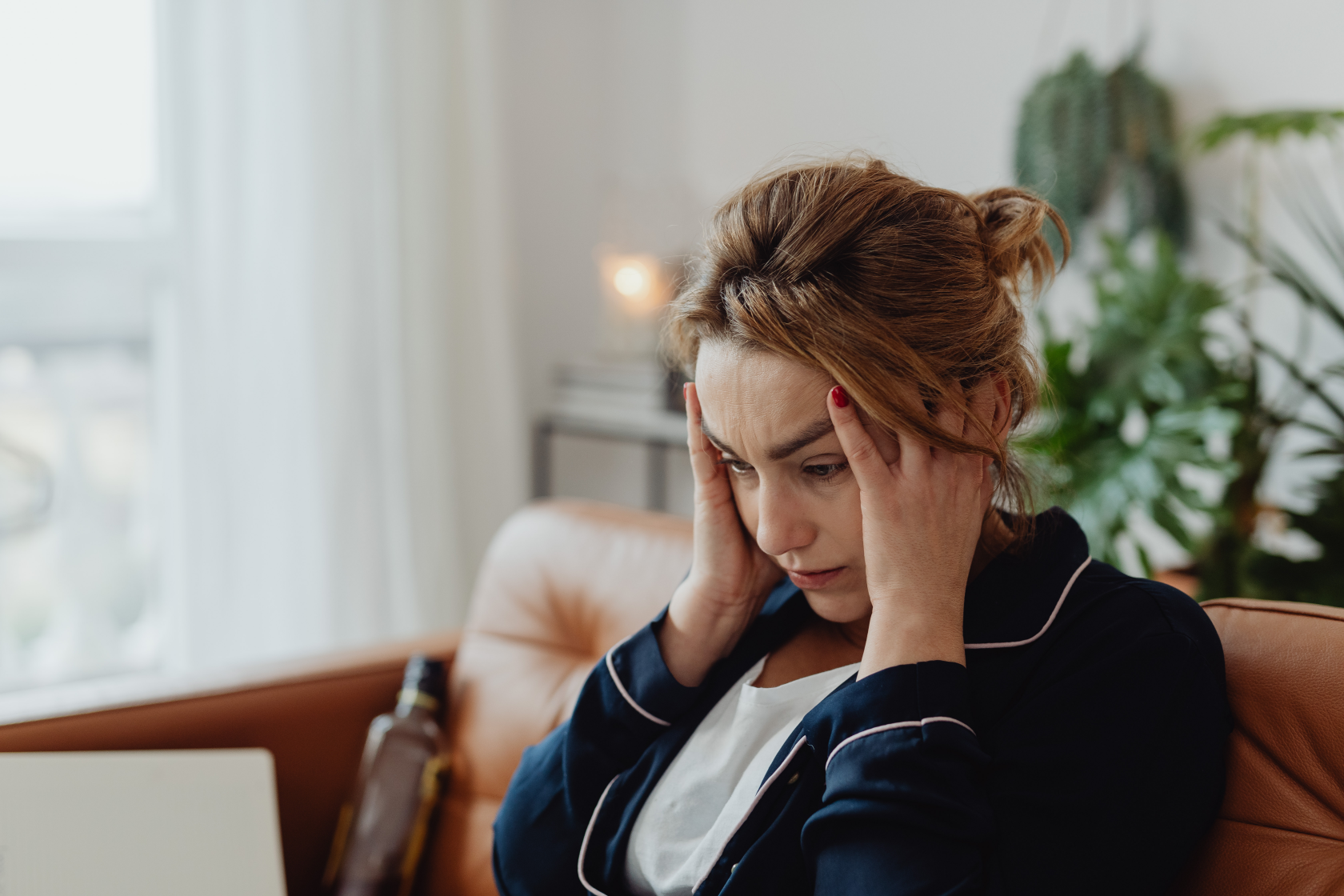 Stressed woman sitting on a couch at home with her head in her hands, looking worried, possibly contemplating missed mortgage payments in Ohio.