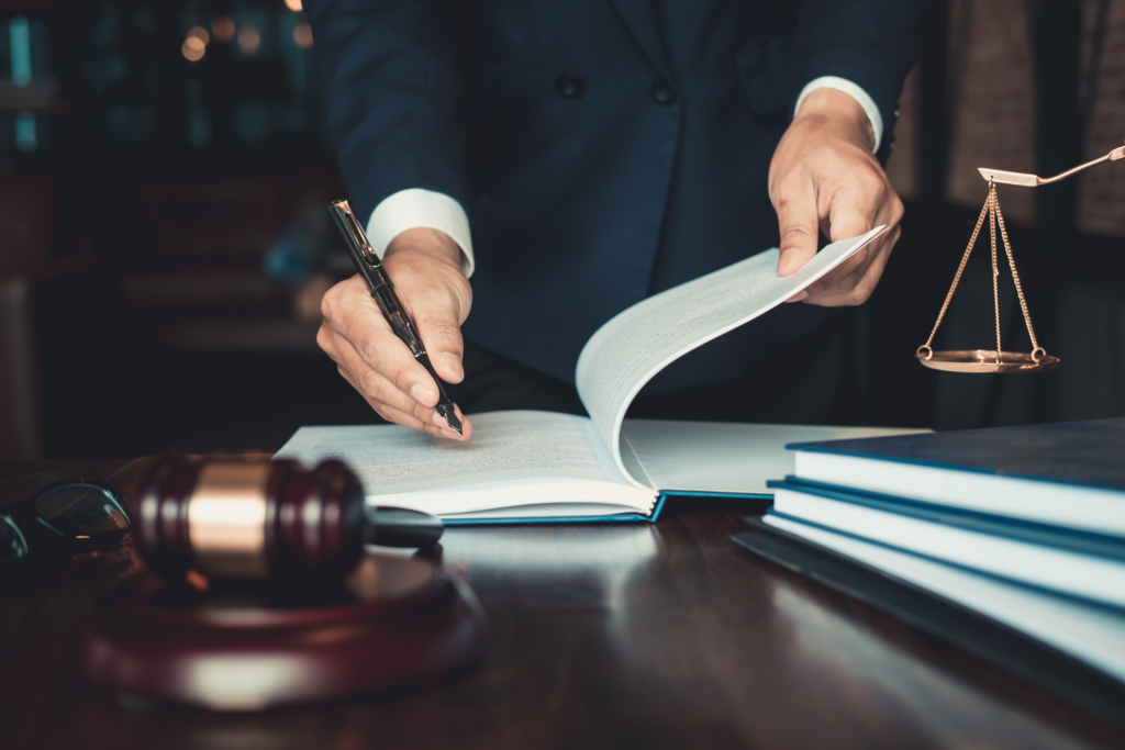 Close-up of a lawyer reviewing legal documents with a pen in hand, scales of justice in the background, symbolizing a homeowner's legal rights and foreclosure process in Ohio.