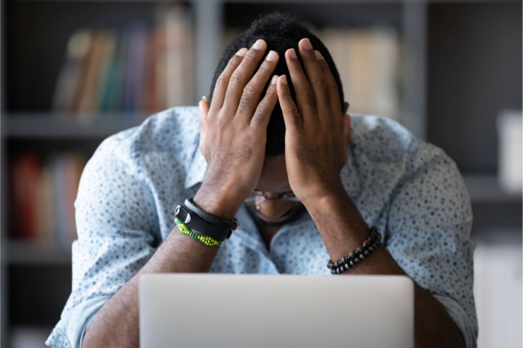 Stressed homeowner facing property tax issues with hands on head while sitting in front of a laptop.