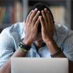 Stressed homeowner facing property tax issues with hands on head while sitting in front of a laptop.