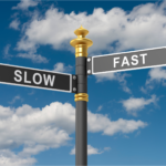 Directional signpost with 'Slow' and 'Fast' arrows against a cloudy sky, symbolizing quick vs slow house selling options in Ohio.