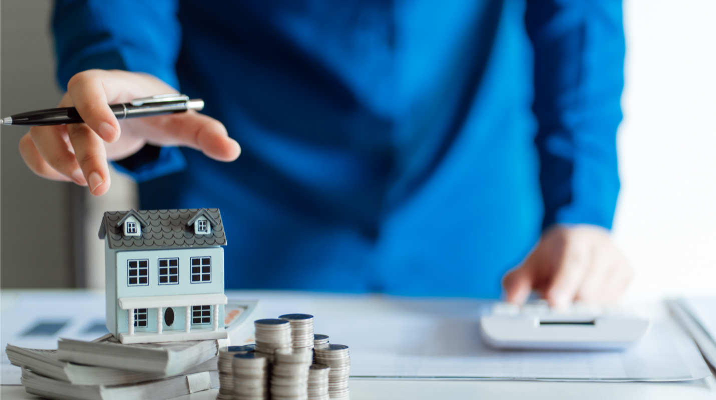 Real estate agent calculating costs with a model house and coins, depicting affordable selling in Toledo, Ohio.