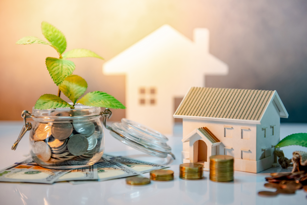 Saving money on Akron home sales with coins, house models, and growing plant representing financial growth.