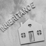 Black and white image of INHERITANCE text with a wooden house silhouette on textured background, symbolizing home inheritance issues.
