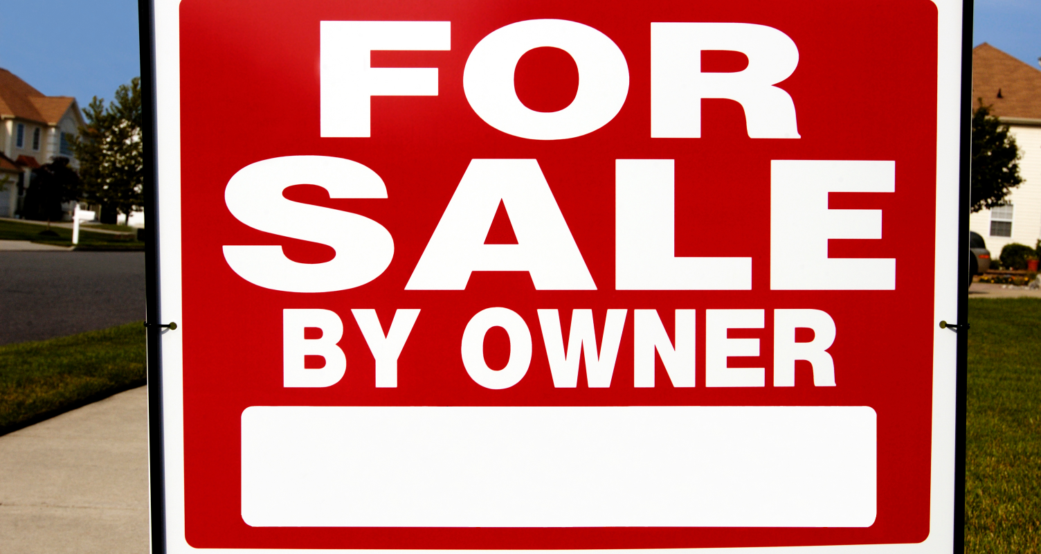 Bold red 'For Sale By Owner' sign on a suburban lawn in Akron, Ohio