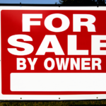 Bold red 'For Sale By Owner' sign on a suburban lawn in Akron, Ohio