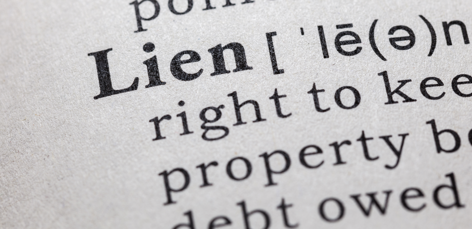 Close-up view of a dictionary definition of 'lien', illustrating the legal right to keep property because of debt, relevant to selling homes with liens in Cleveland.