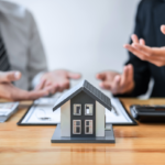 Real estate professionals discussing strategies to sell a house with no equity in Ohio, with a small model house on the table.