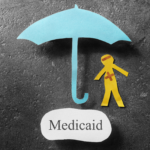 Medicaid coverage protection concept showing a cut-out figure under a blue umbrella with the word 'Medicaid', symbolizing financial safety in Ohio.