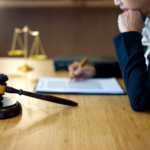 Close-up of a legal professional sitting at a wooden desk, reviewing documents with a pen in hand. A gavel and balance scale are in the background, symbolizing justice. The EZ Sell Homebuyers logo is visible, highlighting real estate legal issues in Ohio.