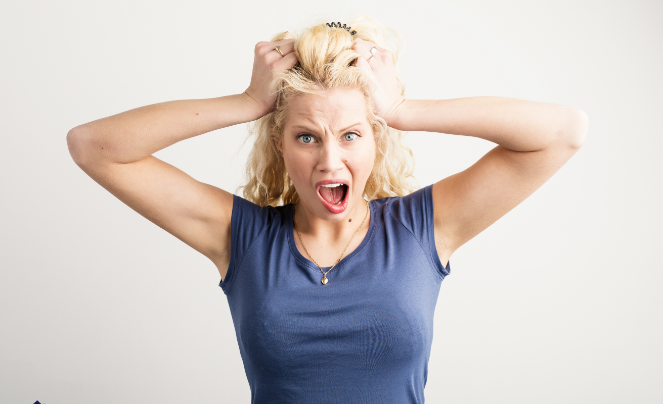 Frustrated woman pulling her hair, representing the stress of a house not selling in Ohio, with solutions including pricing strategies, home appeal improvements, and alternative selling methods.