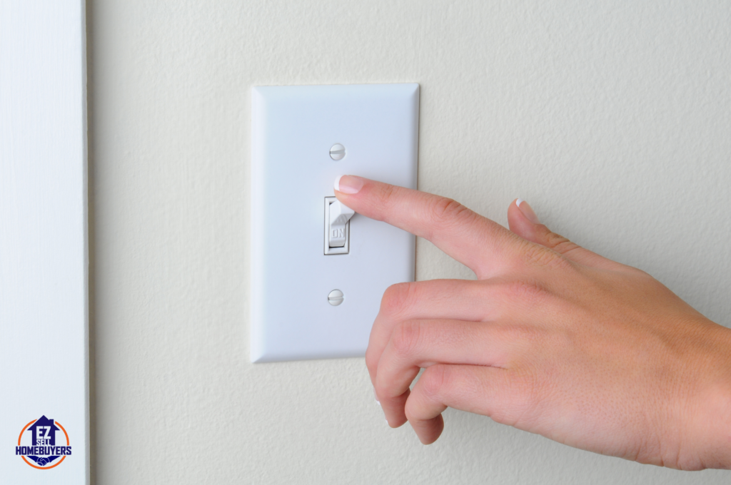 Close-up of a hand turning off a light switch, representing the legal complexities of utility shutoffs for squatters in Ohio as discussed in the article on handling squatter utility management and eviction processes.