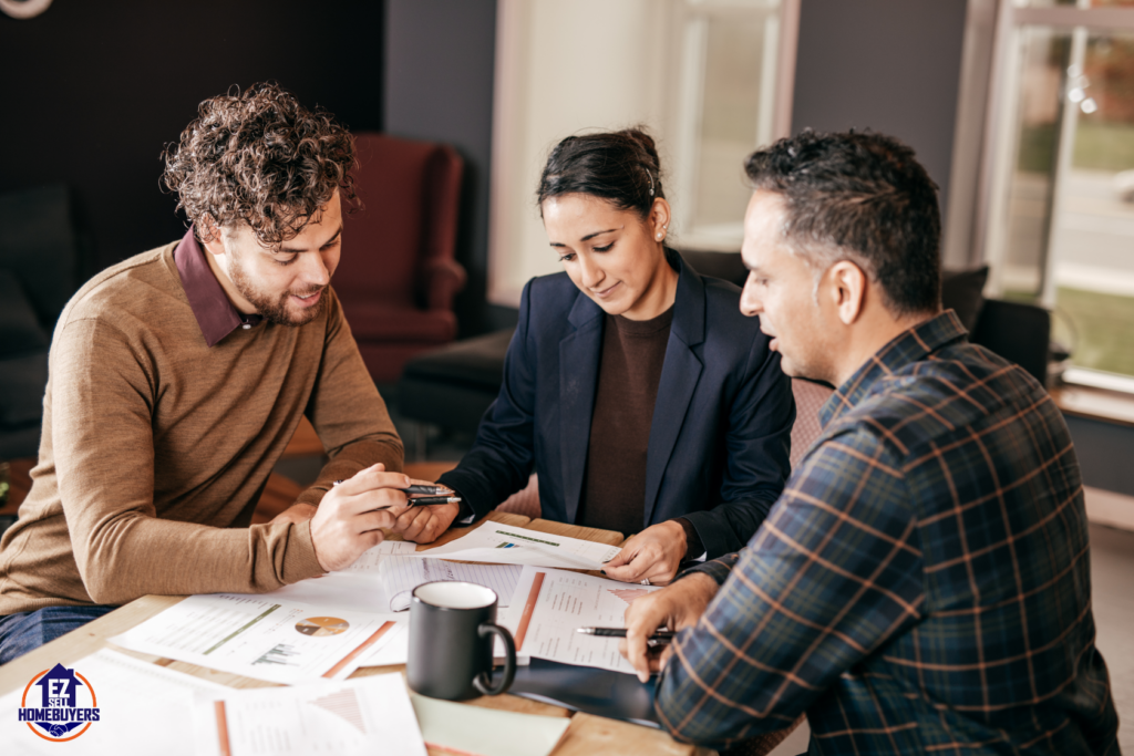 Three people discussing mortgage forbearance options in Ohio at a table with documents, highlighting the process and benefits for homeowners facing financial hardship.