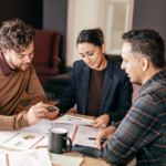 Three people discussing mortgage forbearance options in Ohio at a table with documents, highlighting the process and benefits for homeowners facing financial hardship.