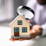 Close-up of a miniature house being inspected with a magnifying glass, representing the Ohio home inspection process. Ideal for real estate buyers or sellers needing home inspection tips.