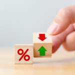 Hand adjusting wooden blocks with percentage symbol and up/down arrows, symbolizing fluctuating interest rates and their impact on the Ohio housing market in 2024.