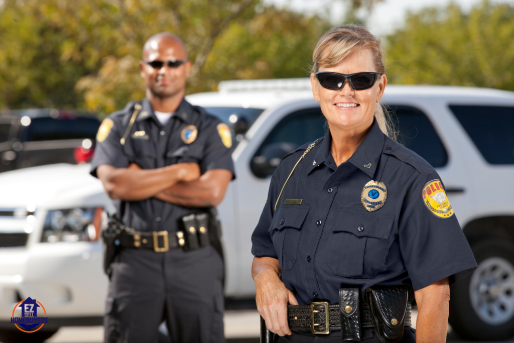 Two Ohio police officers standing confidently in front of patrol vehicles, illustrating law enforcement's role in handling squatter situations and enforcing property rights.