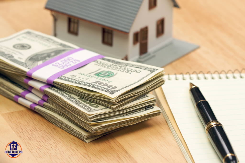 Stacks of cash with a model house and notebook symbolizing the benefits of selling a house for cash in Ohio, highlighting the faster sale process and fewer fees.