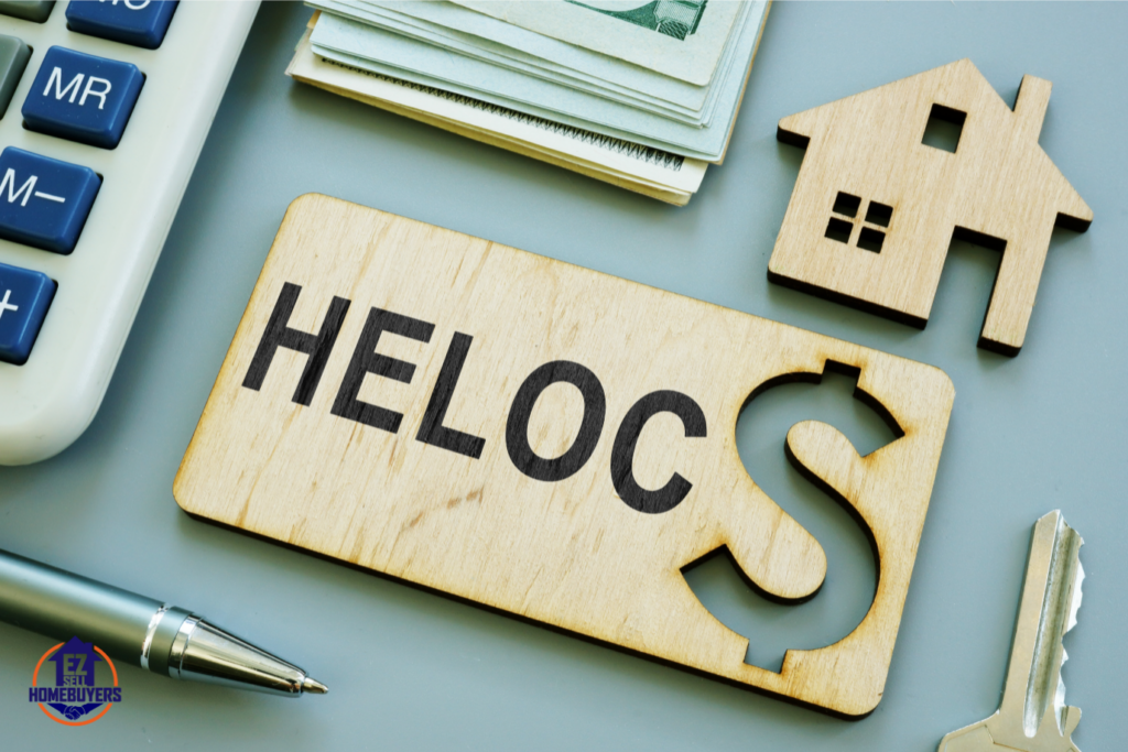 Close-up image of a wooden HELOC sign next to a house model, calculator, and cash, symbolizing financial considerations when selling a house with a HELOC in Ohio.