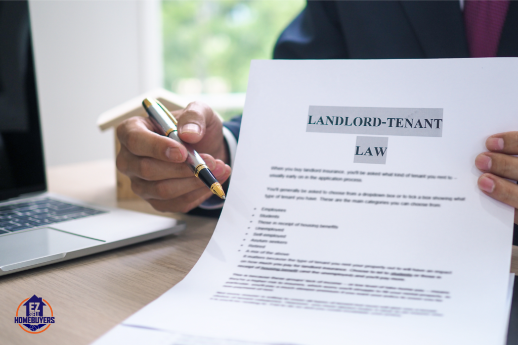 Close-up of a landlord holding a pen and a document titled 'Landlord-Tenant Law' while discussing legal eviction and tenant rights in Ohio, with a laptop and EZ Sell Homebuyers logo in the background.