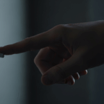 A worried tenant sitting in a dark room in Dayton, Ohio, with only faint daylight coming through the window power appears shut off.