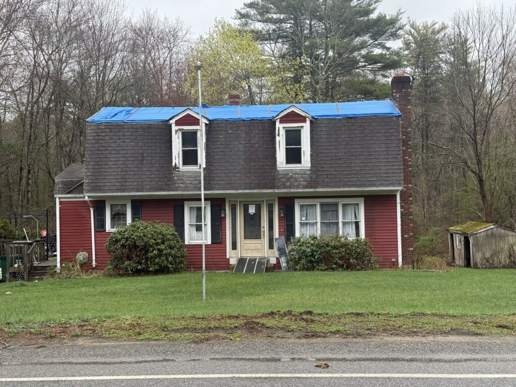 Distressed red house with blue tarp on roof in Halifax MA – sell house as is Halifax Massachusetts