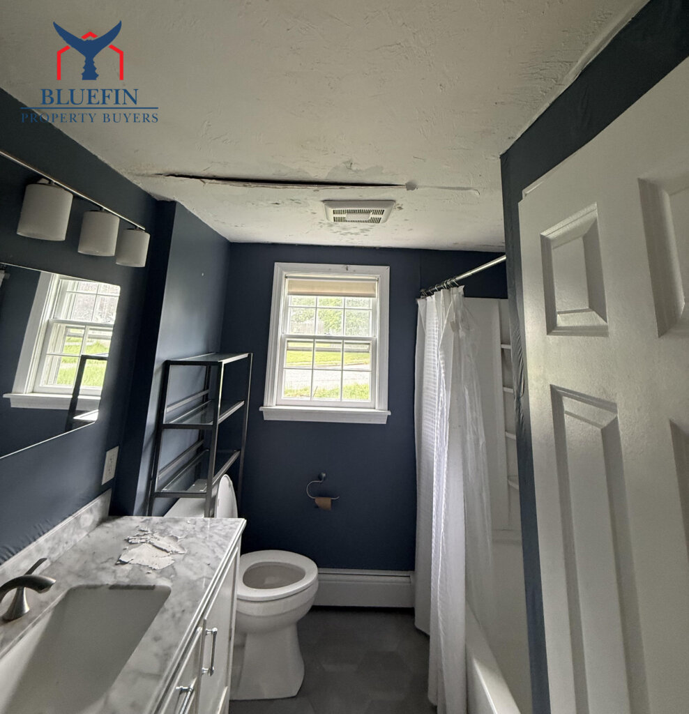 Water-stained and peeling bathroom ceiling below a burst pipe in a Massachusetts home