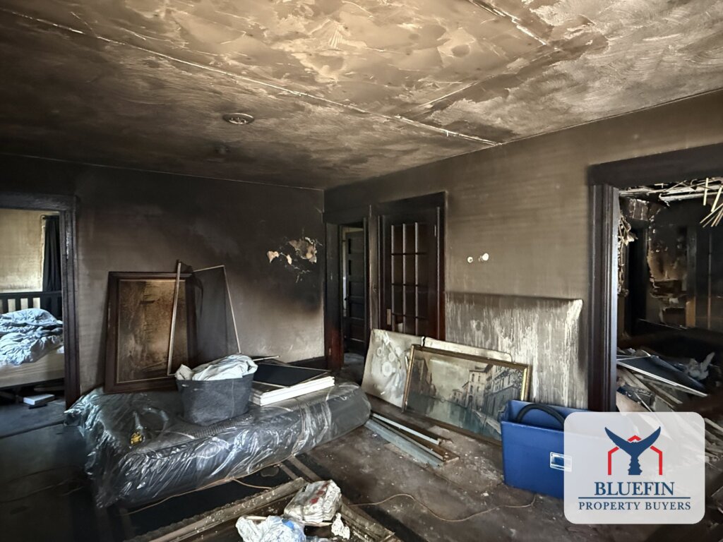 Soot-covered Living Room and stored belongings beside a burned-out room in a Hull, Massachusetts house fire