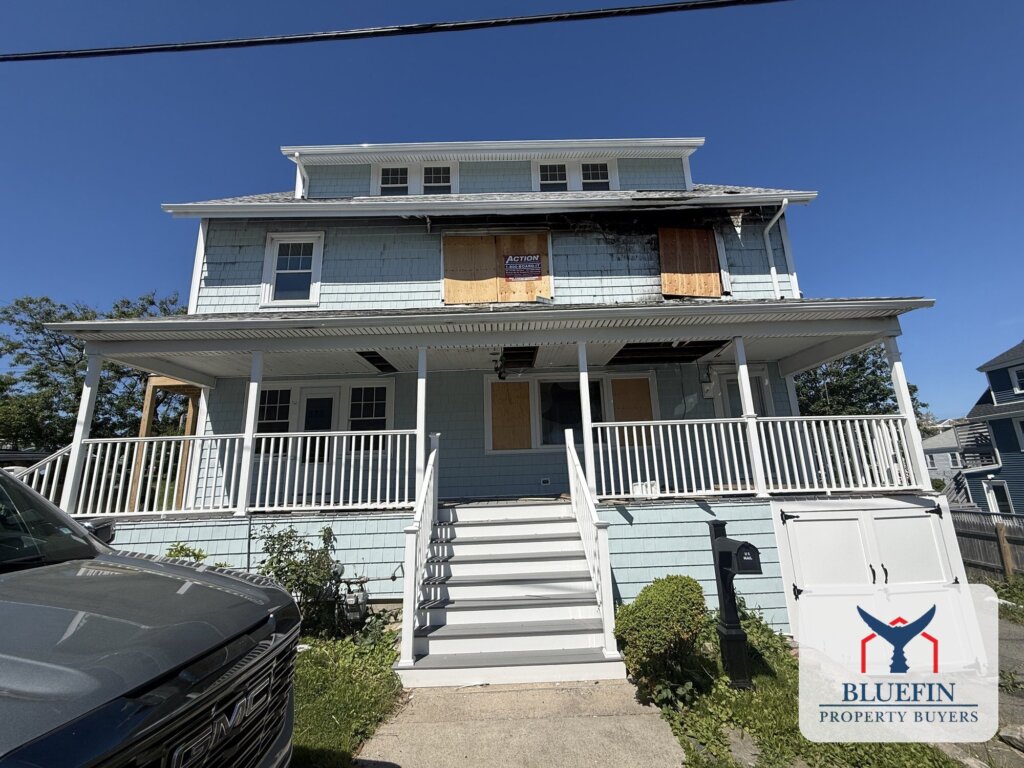 Front of a fully restored Hull, Massachusetts home with boarded second-floor windows and charring after a fire