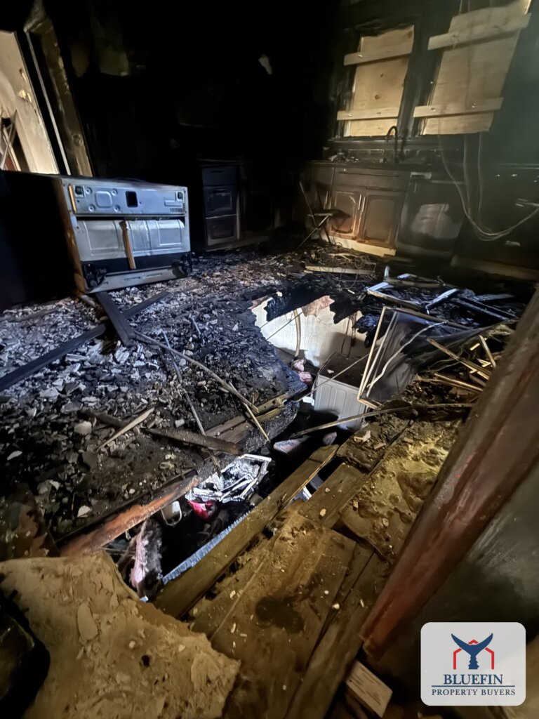 Kitchen floor burned through to the basement in a Hull, Massachusetts house fire, with charred joists exposed