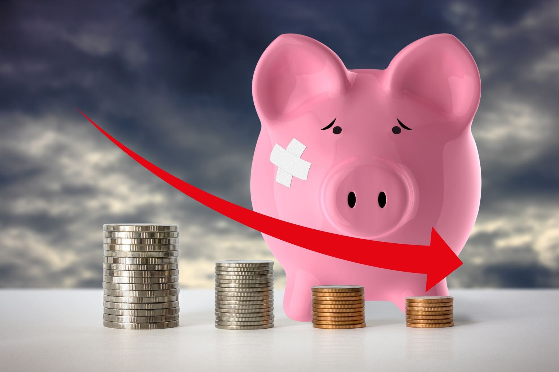 Piggy bank beside shrinking stacks of coins representing the loss of savings value over time.