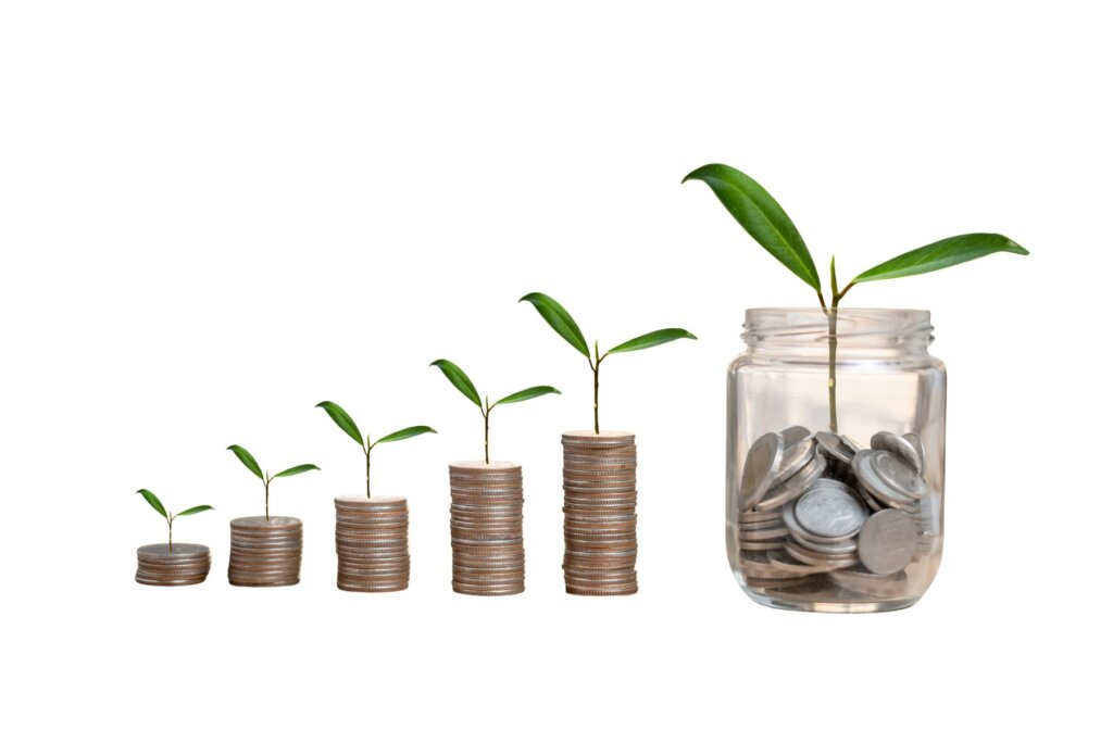 Stacks of coins growing larger with a plant sprouting on top, symbolizing wealth growth through investing.