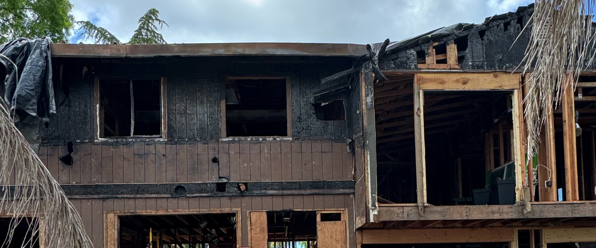 Two-story home with extensive fire damage and exposed framing awaiting major repairs.
