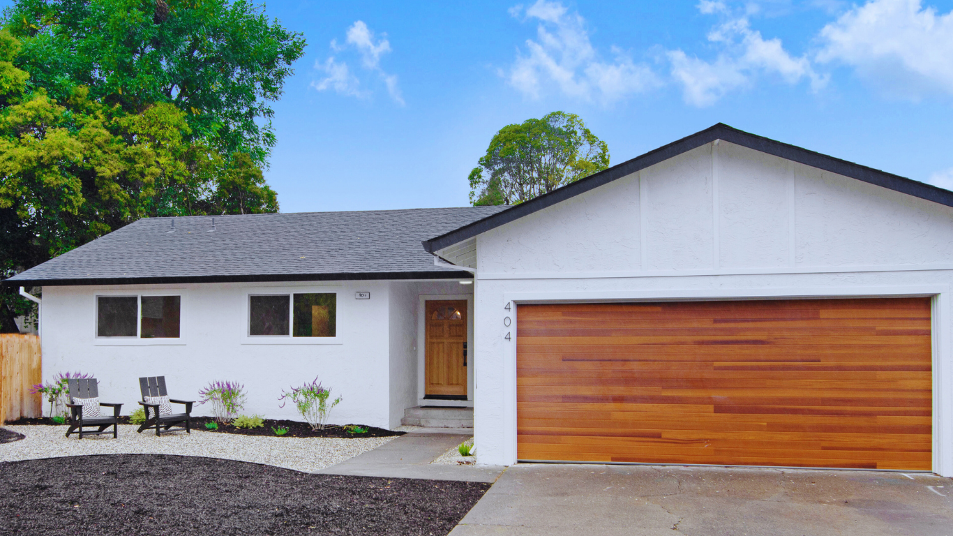Single-story renovated home with white exterior and wood garage door in Rohnert Park, California.