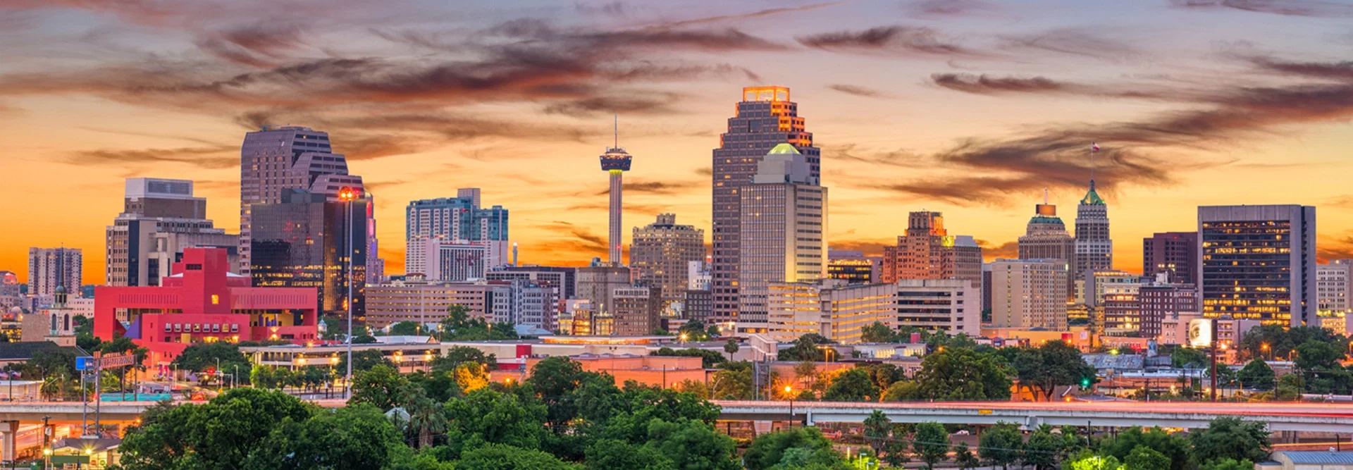 Panoramic view of the San Antonio skyline at sunset with a dramatic orange sky over downtown, representing top rated cash home buyers in San Antonio Texas.