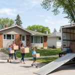 Family carrying boxes out of Winnipeg house to moving truck