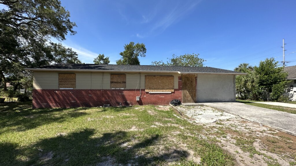 Exterior photo of a house A+ Home Buyers purchased.  House is all boarded up and appears to need a lot of work. 