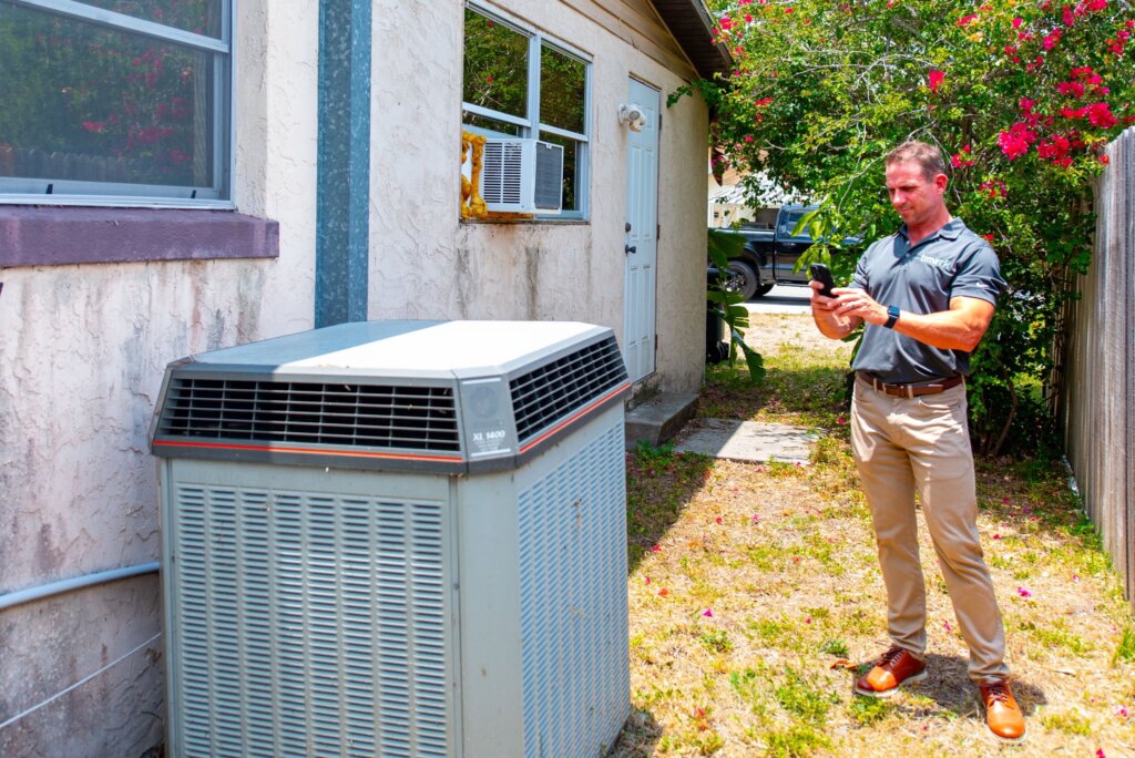 Mike Youngblood taking a picture of the outside a/c unit during his inspection of a home A+ Home Buyers is purchasing.