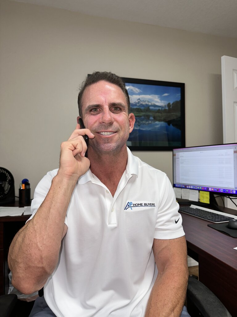 Owner of A+ Home Buyers, Mike Youngblood, talking on the phone in his office with a potential client.