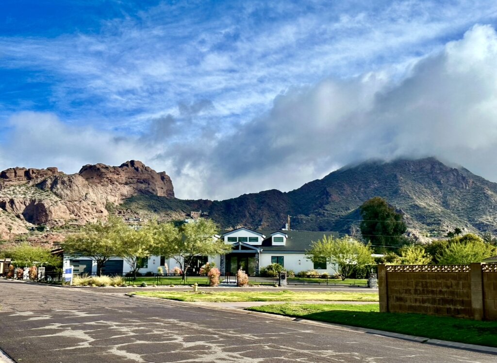 Patriot Flip buys houses for cash in Phoenix, AZ - Modern desert home with agave plants, cacti, and palm trees.
