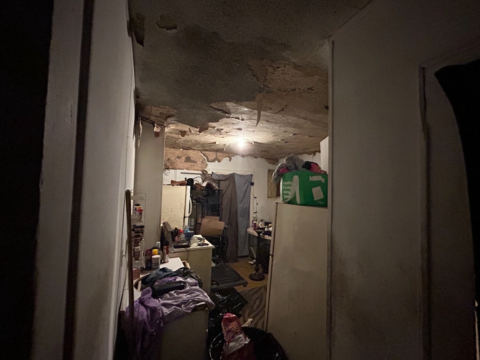 Bedroom in occupied house in Chattanooga, TN, filled with junk and old items, highlighting the need for repairs.